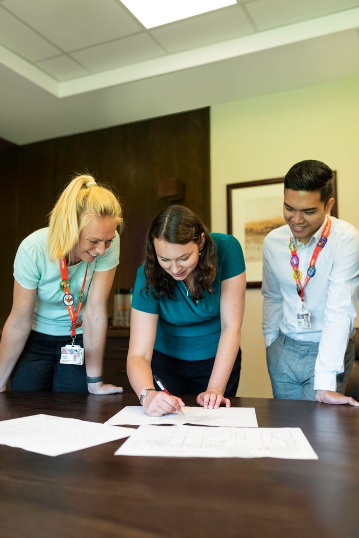 Three colleagues collaborating on a project around an office table, fostering teamwork and cooperation.