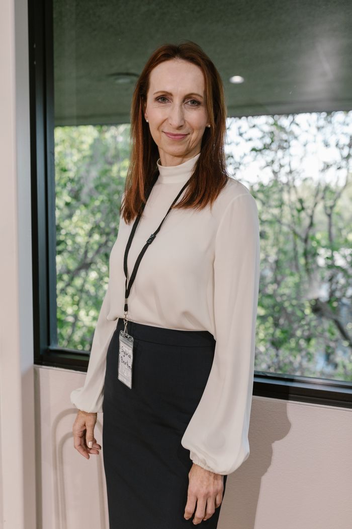 Confident businesswoman in office attire standing near window, exuding professionalism and success.